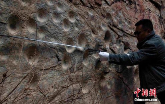 3月14日，调查人员正在测量此次发现的凹穴岩画群。 中新社发 称多县文联 供图