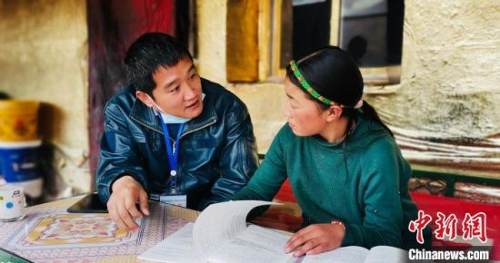 图为樊文斌(左)给牧民家的孩子辅导功课。　甘德县委宣传部 供图