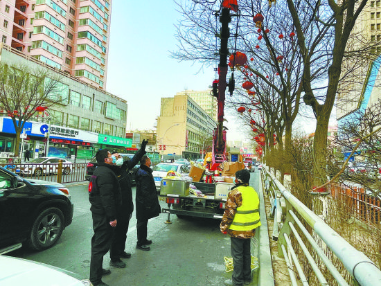 工作人员查看道路两旁悬挂的红灯笼。摄影：王晶