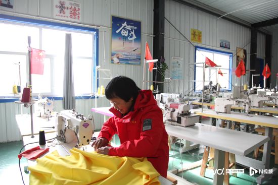 韩新庄姐在服装厂的工位上缝制衣服。
